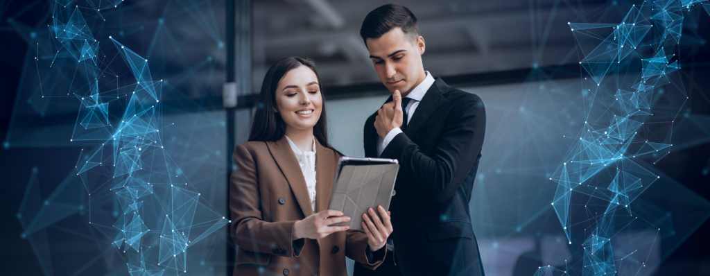 Dois profissionais de negócios, uma mulher em blazer marrom e um homem em terno preto, observam um tablet com expressões de colaboração. Ao redor, gráficos de linhas que sugerem tecnologia e comunicação digital.