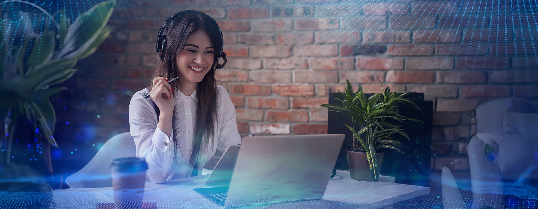 Mulher sorridente com headset, trabalhando em um laptop, em um ambiente moderno com tijolos à vista e plantas ao fundo, representando atendimento remoto profissional e tecnológico.