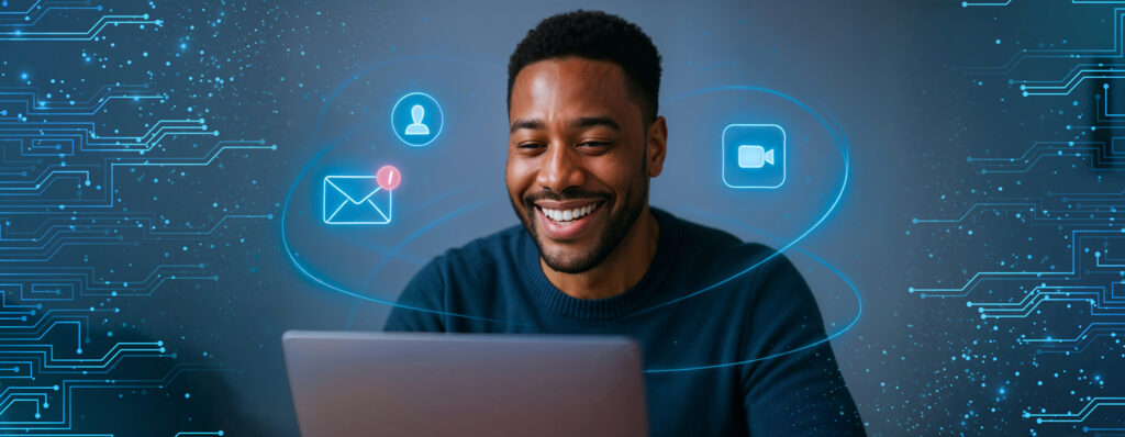 Homem sorrindo enquanto utiliza um notebook, com ícones digitais de e-mail, vídeo e usuário flutuando ao seu redor em um ambiente tecnológico.